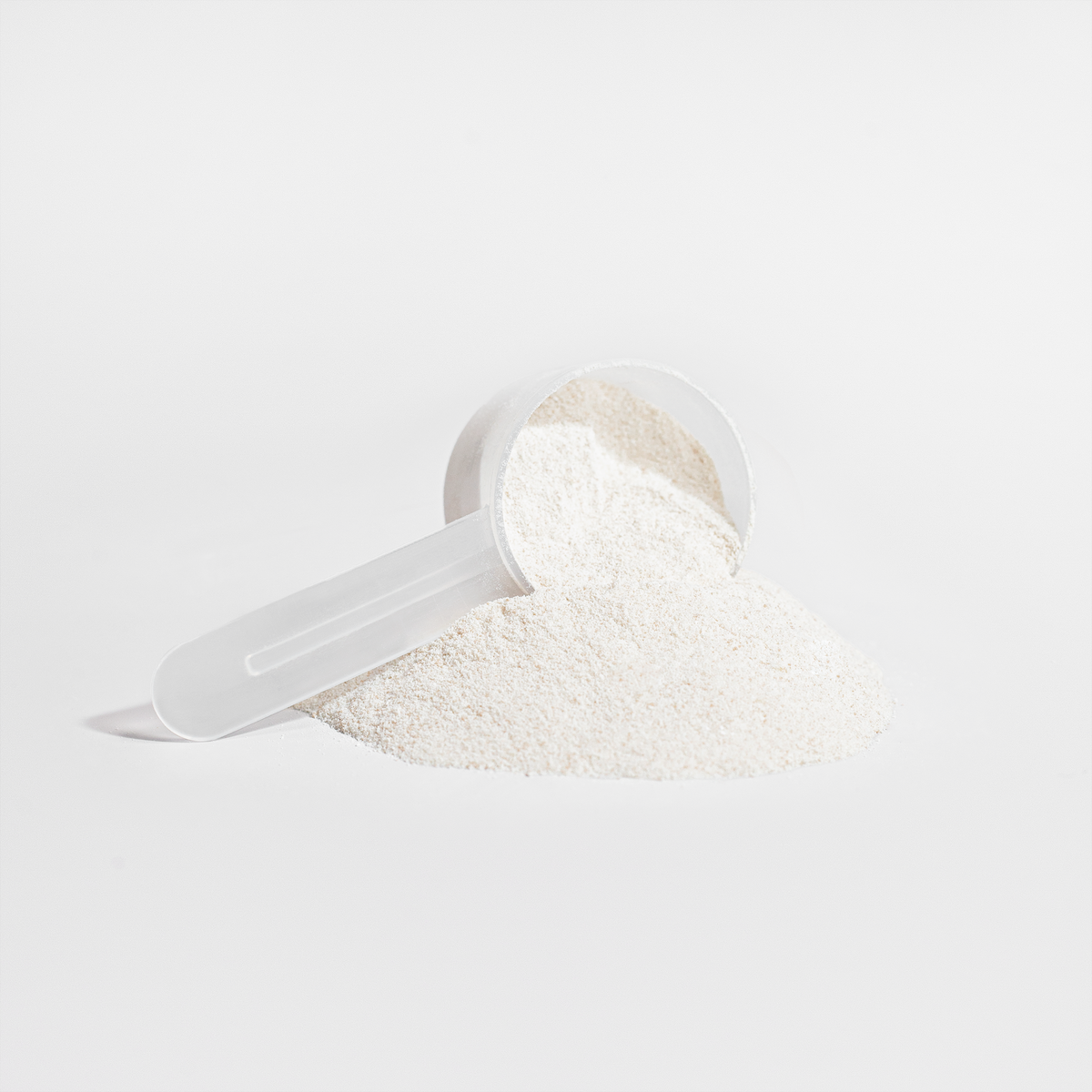 Grass-Fed Collagen Creamer Vanilla in a scoop with powder spilled on a white surface.