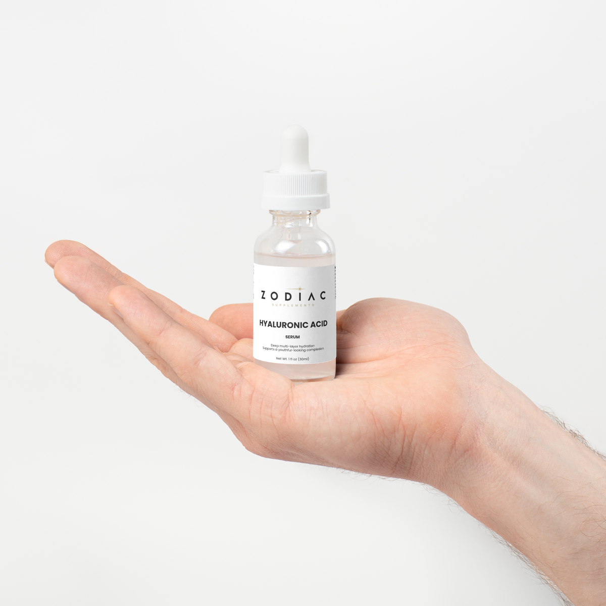 Hyaluronic Acid Serum in a dropper bottle held in hand against a white background.